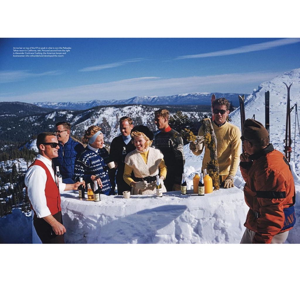 Group of people enjoying a meal in the snow with mountains in the background