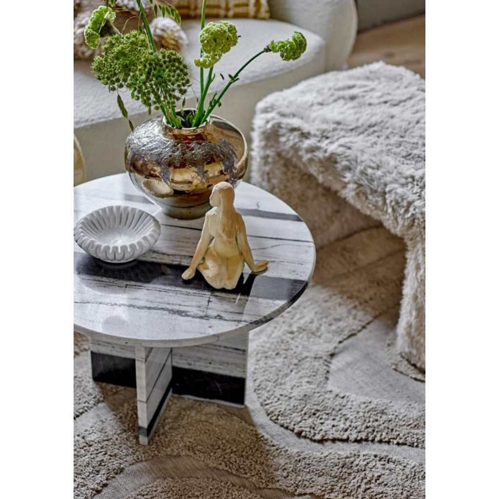 Round wooden coffee table with decorative items in a cozy living room setting.