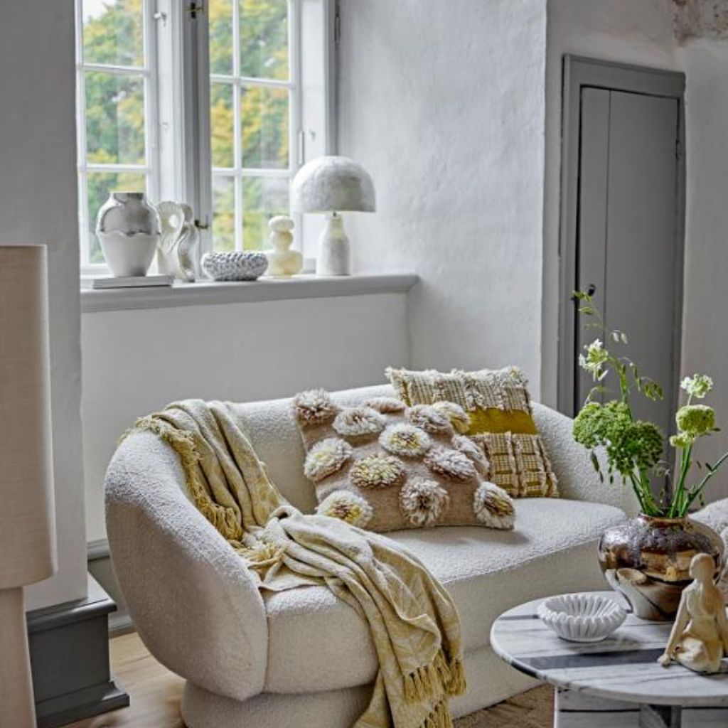 Cozy living room with a white sofa, decorative pillows, and a small table with plants.