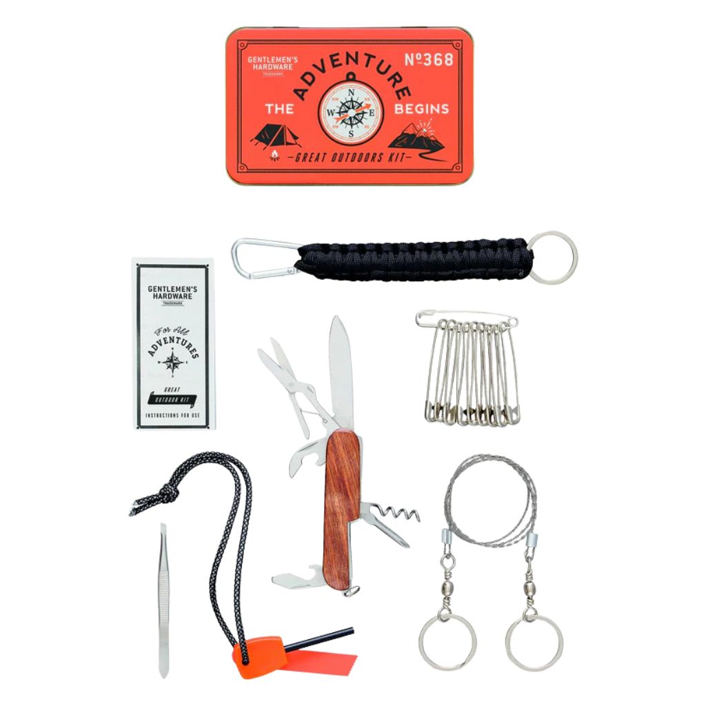 A collection of survival tools including a penknife, safety pins, tweezers, rope, fire starter, and a tin case with 'The Adventure Begins' text.