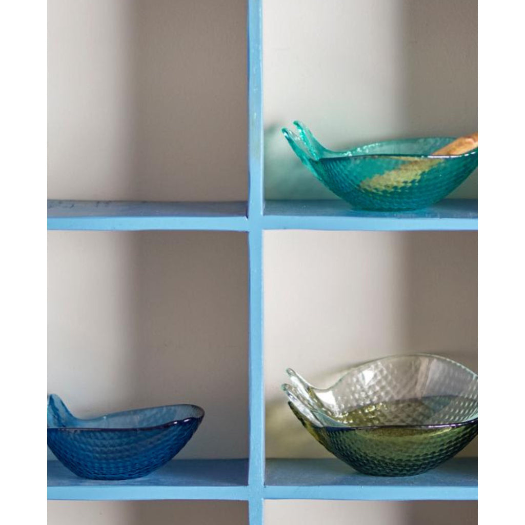 Three glass bowls on a blue shelf against a neutral wall