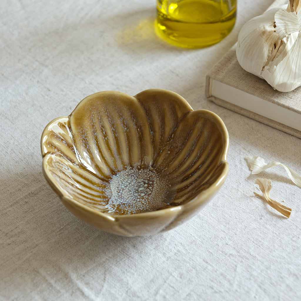 Decorative ceramic bowl on a textured surface with a bottle of oil and garlic in the background.