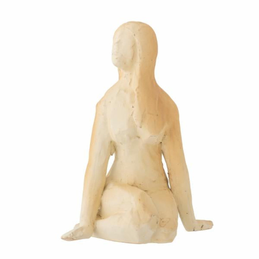 Statue of a nude figure sitting on a white background
