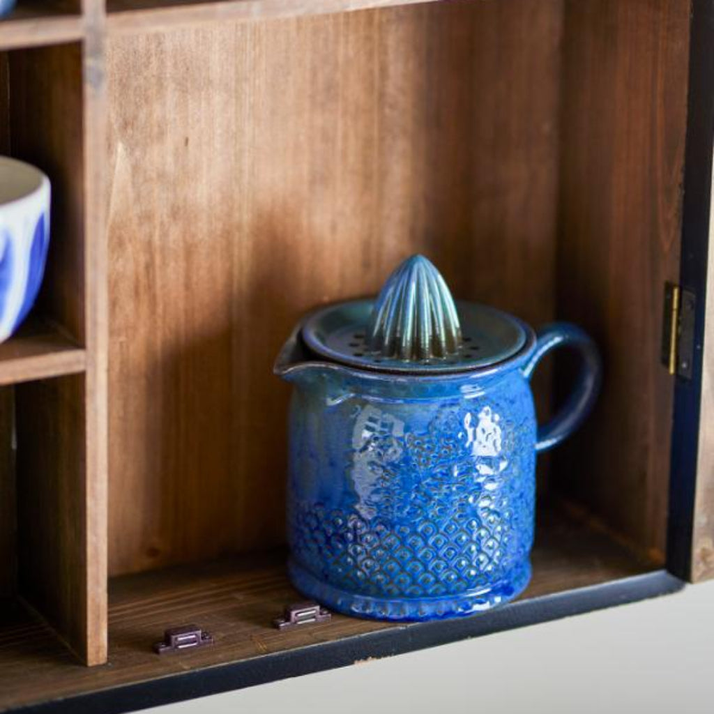 Blue ceramic juicer on a wooden shelf