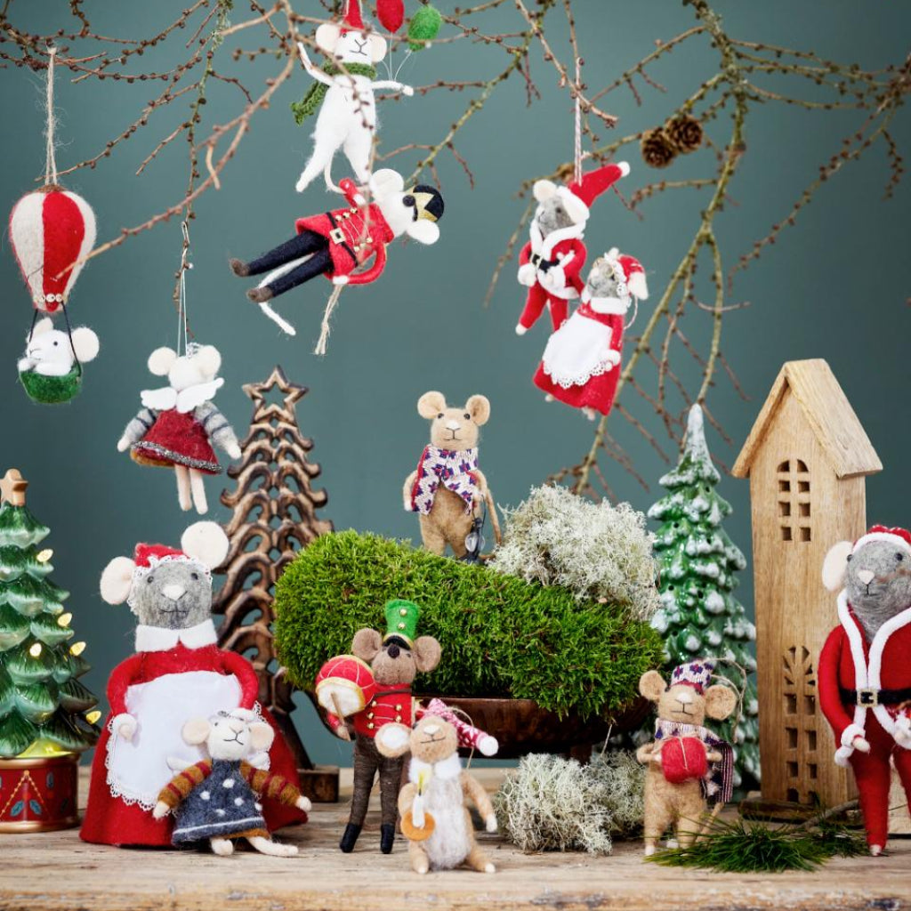 Christmas-themed decorations with toy mice and festive elements on a wooden surface.