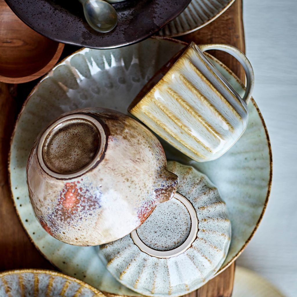 Collection of ceramic teapots and cups on a wooden surface with a blurred background